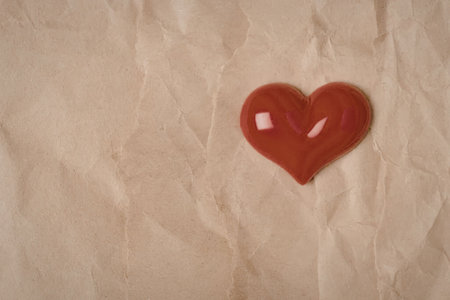 A shiny red heart on a crumpled brown paper backgroundの写真素材