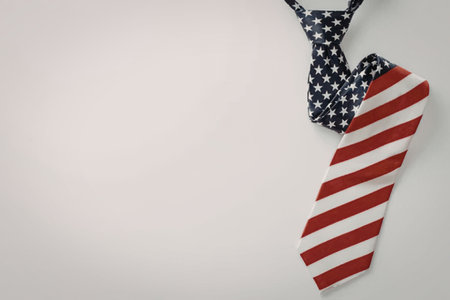 A patriotic combination of a tie with an American flag design and another tie with a starry blue pattern, both hanging on a white background.の写真素材