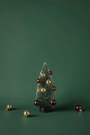 A small Christmas tree decorated with red and gold ornaments on a green background