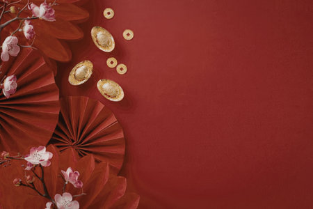 A red background with red paper fans, pink flowers, and gold coins, symbolizing good fortune and prosperity.の写真素材
