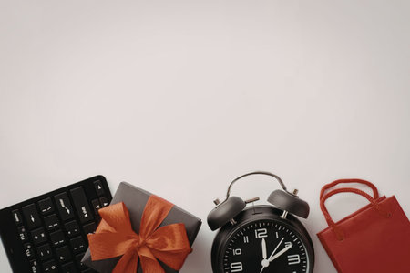 A black keyboard, a gift box with a red bow, an alarm clock, and a red shopping bag on a white...