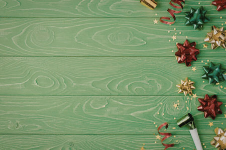 A green wooden background with Christmas decorations including bows and ribbons