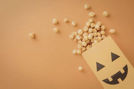 A jack-o-lantern face on a yellow bag with candy corn spilling out on an orange background.の写真素材