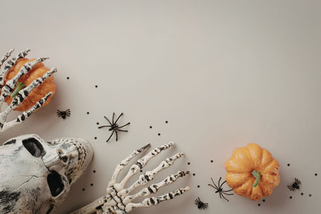 A Halloween-themed decoration featuring a skeleton head and hand, two small pumpkins, and several...