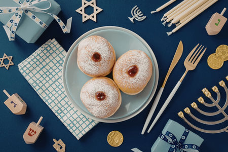 A plate of sufganiyot, traditional Hanukkah jelly donuts, surrounded by Hanukkah-themed items.