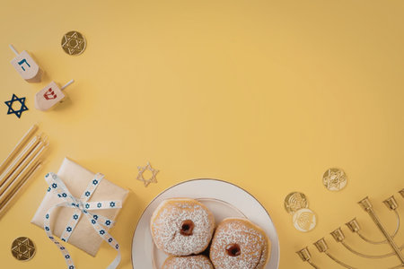 A plate of sufganiyot, dreidels, and other Hanukkah symbols on a yellow backgroundの写真素材