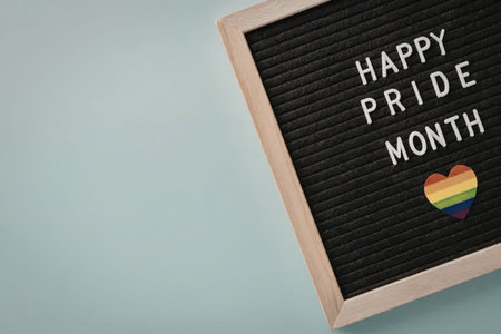 A sign celebrating Pride Month with a rainbow heart on a light blue background