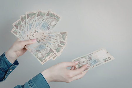 A person holding a large fan of euro banknotes in one hand and a single note in the other.