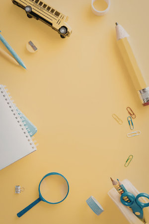 A collection of school supplies on a yellow background including a school bus, pencil, notebook, and...