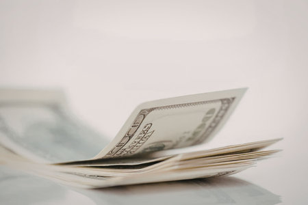 A stack of US dollar bills on a table with a plain white background