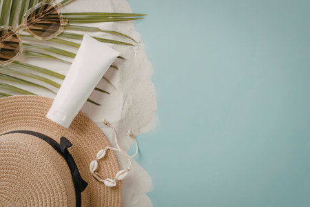 A straw hat, sunscreen, feather, and palm leaves on a light blue background