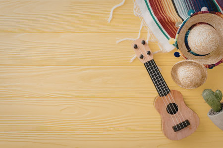 A ukulele, sombrero, and coconut shells on a yellow wooden background