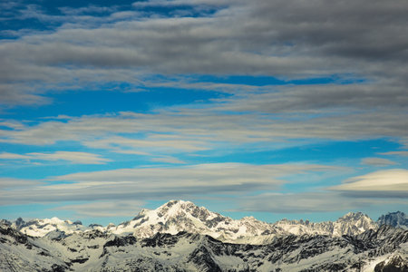 Snowy mountains under blue sky with clouds. Mount Disgrazia, a well-known mountaineering destination in the Bregaglia Alpine Rangeの写真素材