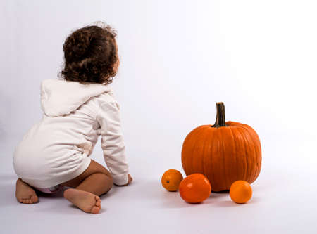 little girl playing with orange fruitsの写真素材