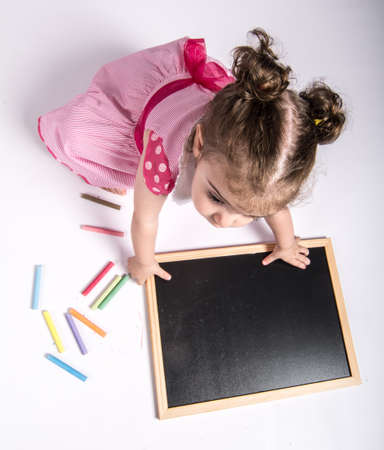 little girl with blackboard and colored chalksの写真素材