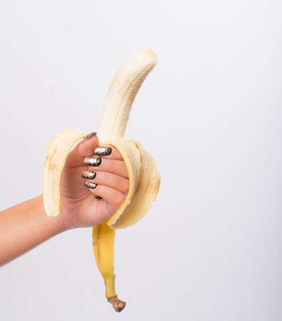 hand with painted nails clutching a bananaの写真素材