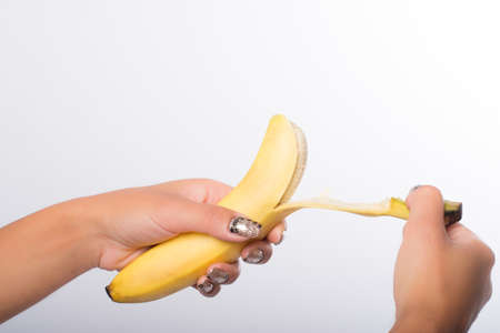 hand with painted nails clutching a bananaの写真素材