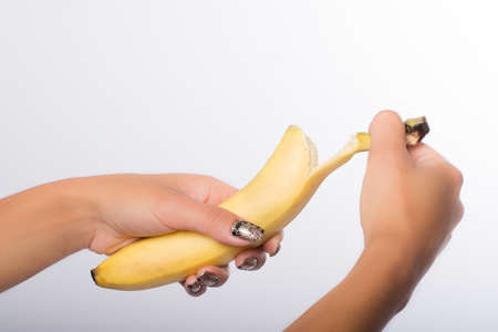 hand with painted nails clutching a bananaの写真素材