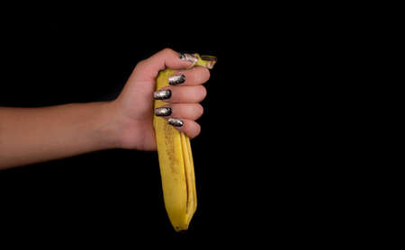 hand with painted nails clutching a bananaの写真素材