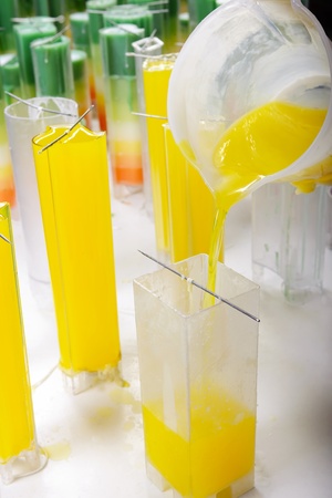 Candle manufacture , pouring colorful molten yellow wax into plastic moulds のeditorial素材