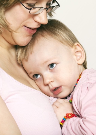 A beautiful baby girl cuddles up in the safety and love of her mothers chest,mother looking down, close-up facial expressions. の写真素材