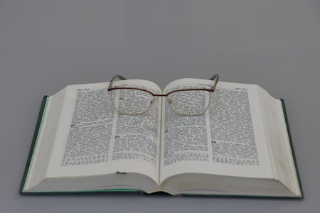 Glasses on the Holy Bible on a gray background, close-up