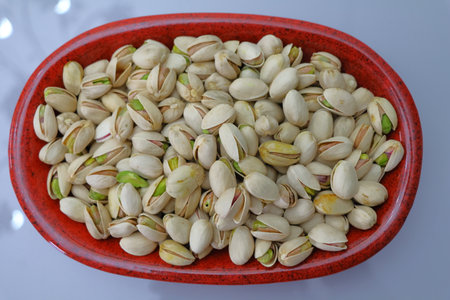 Pistachios nuts in a bowl on a white background.