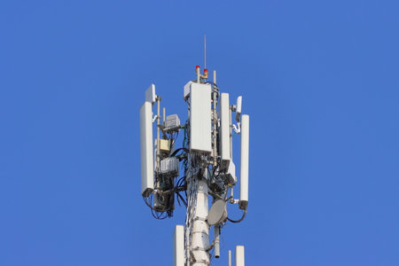 Telecommunication tower with antennas on blue sky background, closeup of photo
