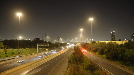 A view of a highway at night with traffic lights in the foreground.