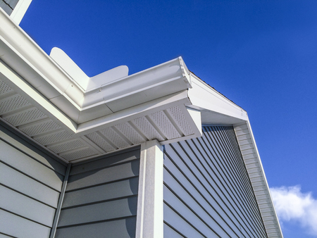 New white colored gutters, soffit, siding and facia on home. Blue sky in the background.