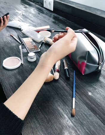 The model applies makeup before the photo shoot with various cosmetics lying on the table in the studio.の写真素材