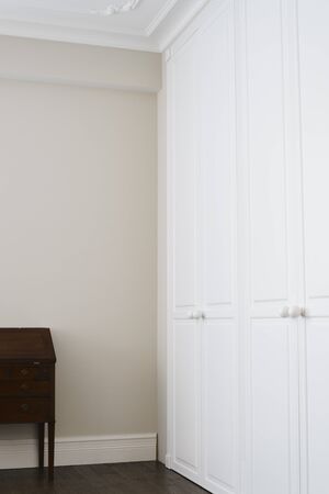 White cabinet doors with brown floor handles and a brown chest of drawersの写真素材