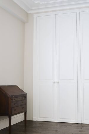 White cabinet doors with brown floor handles and a brown chest of drawersの写真素材