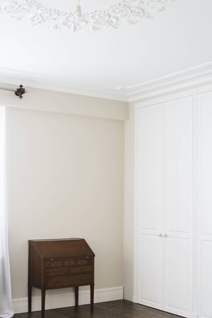 White cabinet doors with brown floor handles and a brown chest of drawersの写真素材
