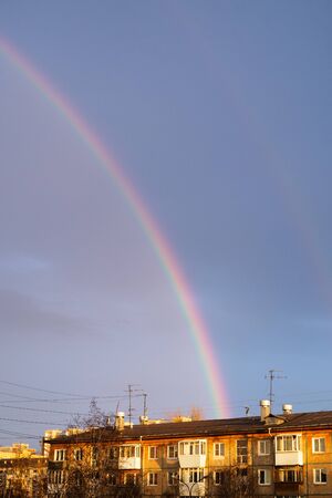 Multi-colored rainbow after the rain passing over the housesの写真素材