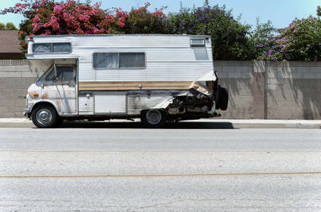An old and dilapidated recreational vehicle sits on a residential street.の写真素材