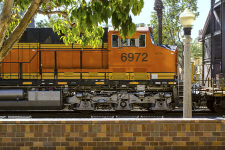 A freight train passes by a commuter station.