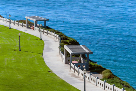 A scenic walkway winds along the top of a cliff overlooking the sea.の写真素材