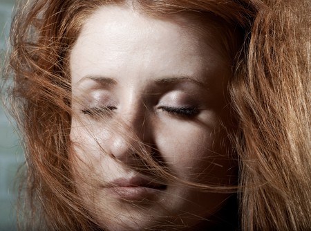 Redhaired mysterious woman against brick wall .