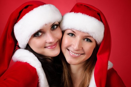Two girl friends in christmass costumes on white. Close-up.の写真素材