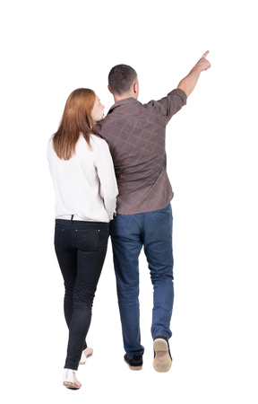 Back view of walking young couple (man and woman) pointing. Rear view people collection. backside view of person. Isolated over white backgroundの写真素材