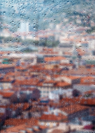 Autumn, rainy city through a window with raindrops. autumnal mood.の写真素材
