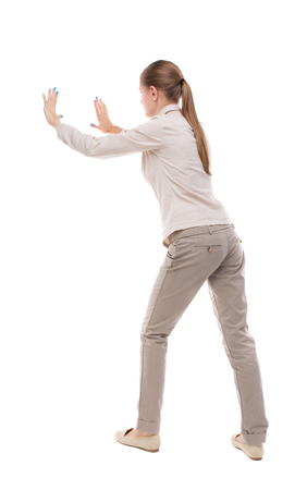 back view of woman pushes wall. Isolated over white background. Rear view people collection. backside view of person. Girl with long hair in a white jacket repelledの写真素材