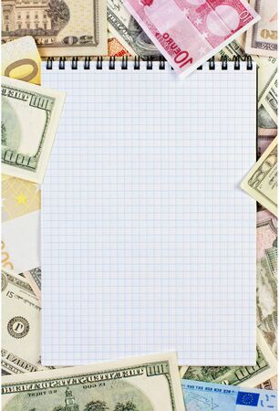 Opened spiral notepad (notebook) sheet in a cage on money background ( euro and dollars cash)の写真素材