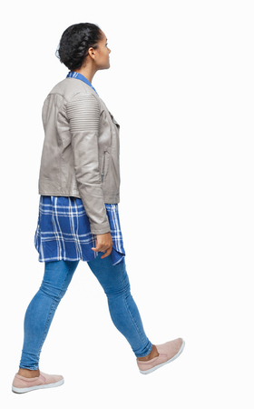 back view of a young black girl walking in jeans and a checkered shirt. beautiful girl in motion. backside view of person.  Rear view people collection. Isolated over white. African American in autumn clothes walking down the street.の写真素材