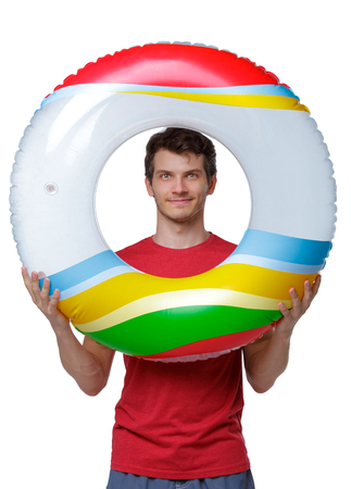 Front view of a man in shorts with an inflatable circle. guy on the beach. Rear view people collection.  backside view of person.  Isolated over white background. Beach tourist looks through the inflatable circle.の写真素材