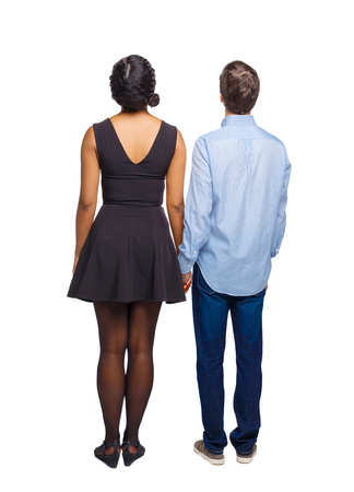 Back view of the interracial couple. friendly girl and guy together. Rear view people collection.  backside view of person. Isolated over white background. Multi-ethnic couple looking up holding hands.の写真素材