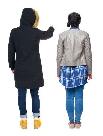 Back view of two pointing young girl in winter jacket. Rear view people collection. backside view of person. beautiful woman friends showing gesture. Rear view. Isolated over white background.の写真素材