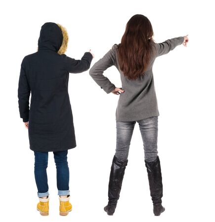 Back view of two pointing young girl in winter jacket. Rear view people collection. backside view of person. beautiful woman friends showing gesture. Rear view. Isolated over white background.の写真素材