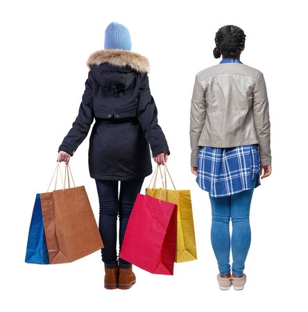 back view of two women with shopping bags in winter jacket. backside view of person. Rear view people collection. Isolated over white background. Two girls with bags stand next procurement.の写真素材